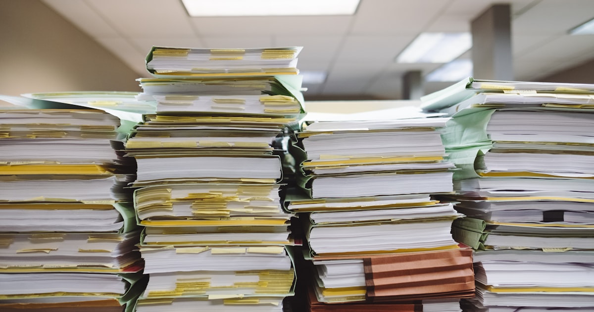Pilhas de documentos e fichas de papel, representando dados de pacientes