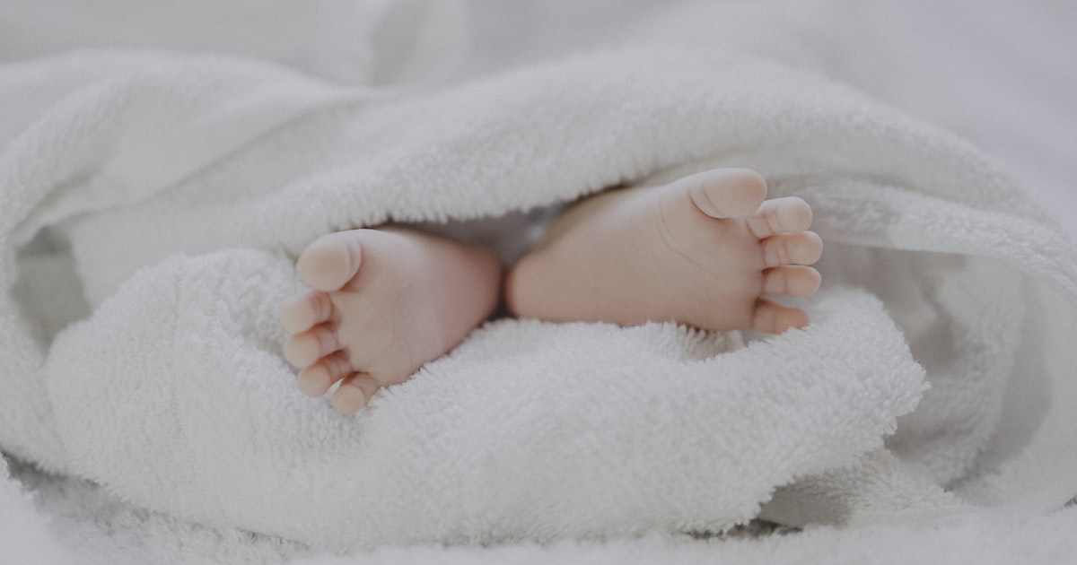 Pés de um bebê recém-nascido envoltos em uma manta branca