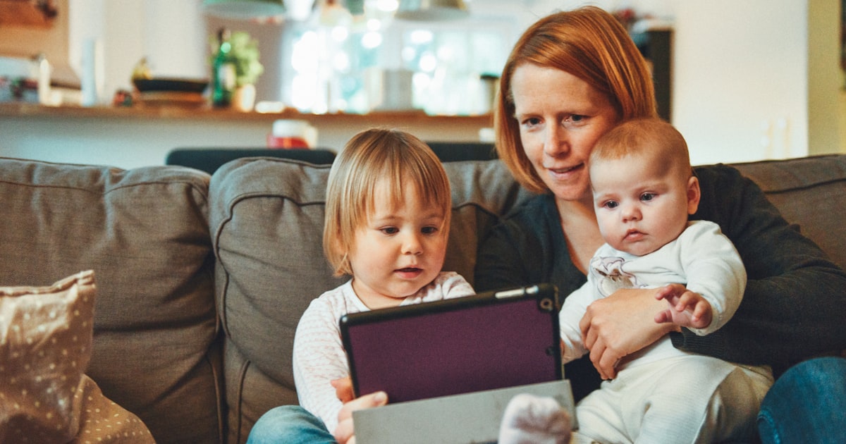 Mãe com dois filhos pequenos no sofá