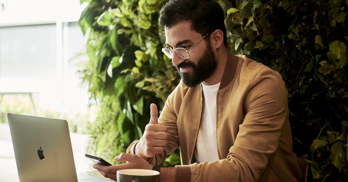 Profissional sorrindo, com o celular na mão, durante um atendimento