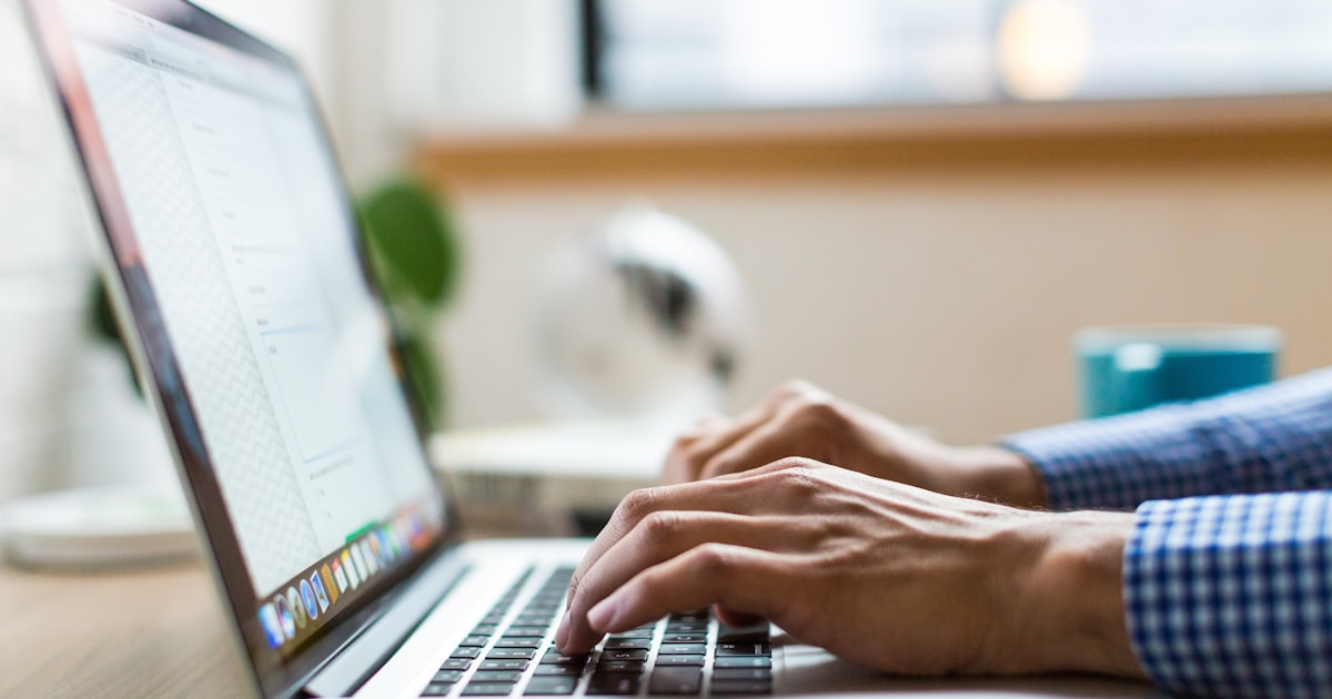 Mãos digitando em um laptop, representando o atendimento médico on-line