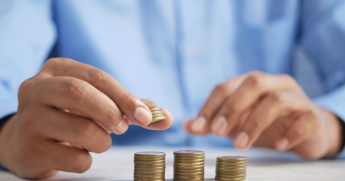 Mãos empilhando moedas, representando planejamento financeiro e tributário